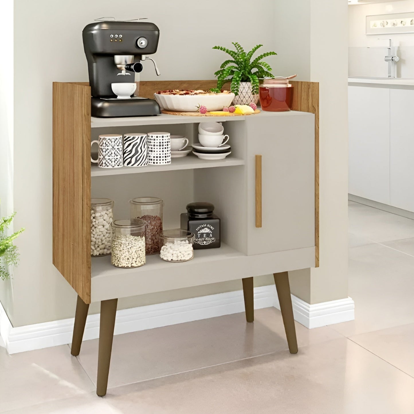 Small kitchenette with a coffee maker, cups, and a plant on a light-colored floor.