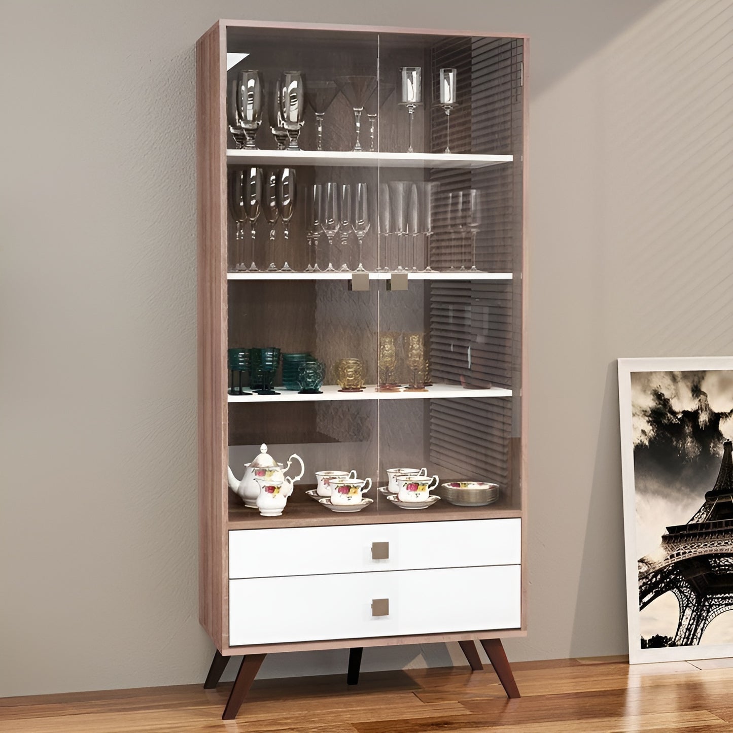 Tall glass display cabinet with various glassware against a neutral wall.