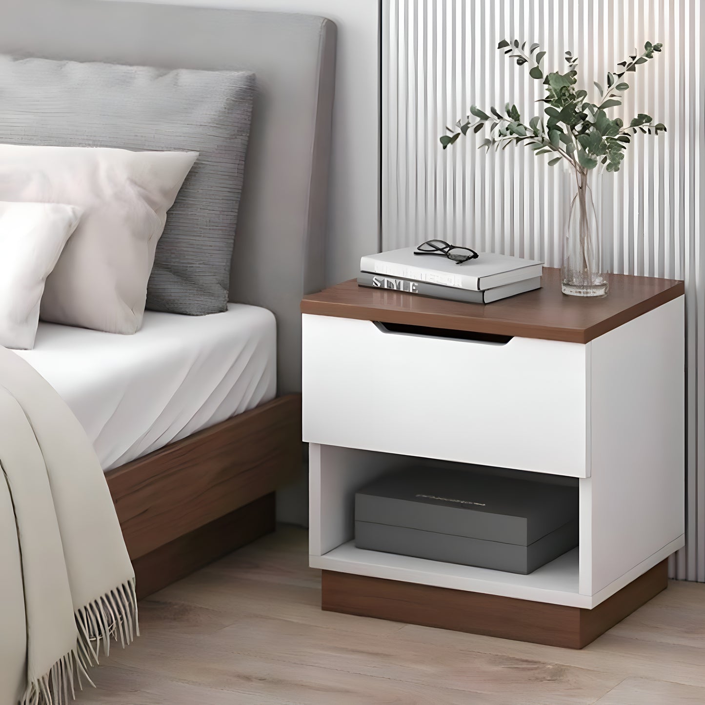 White nightstand with wooden top next to a bed with gray and white pillows.