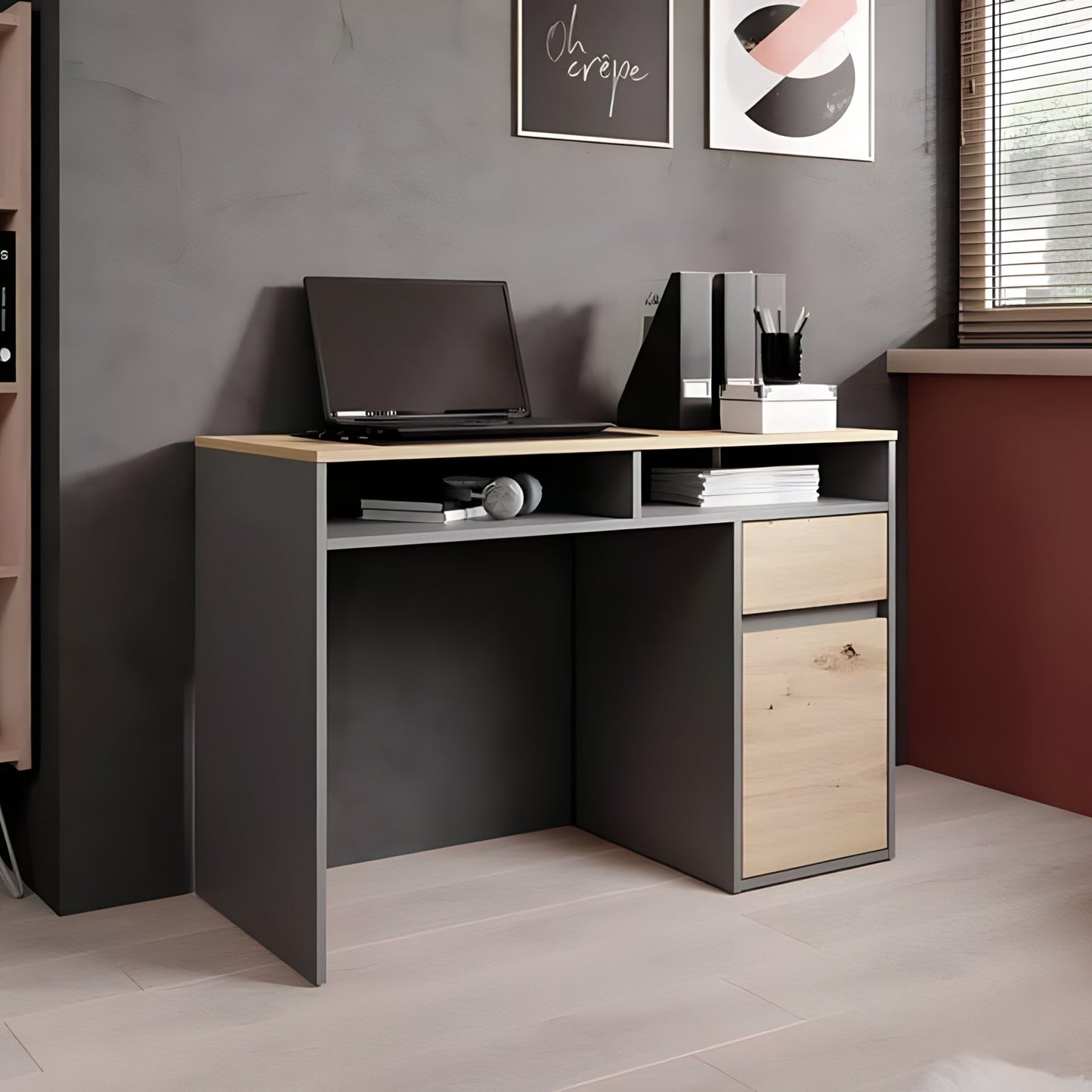 Modern office desk with a laptop and books in a room with a bookshelf and window.