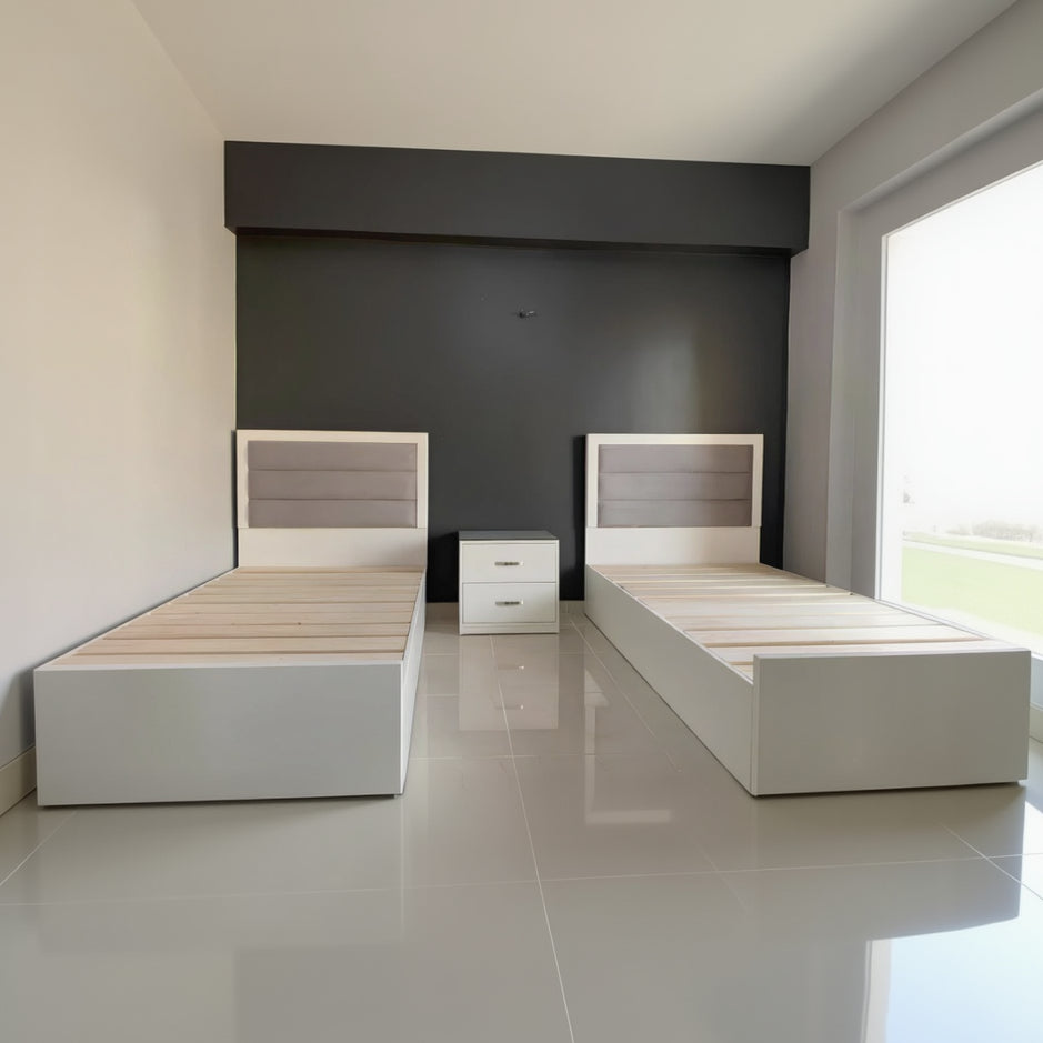 Two wooden beds with white frames against a dark wall.
