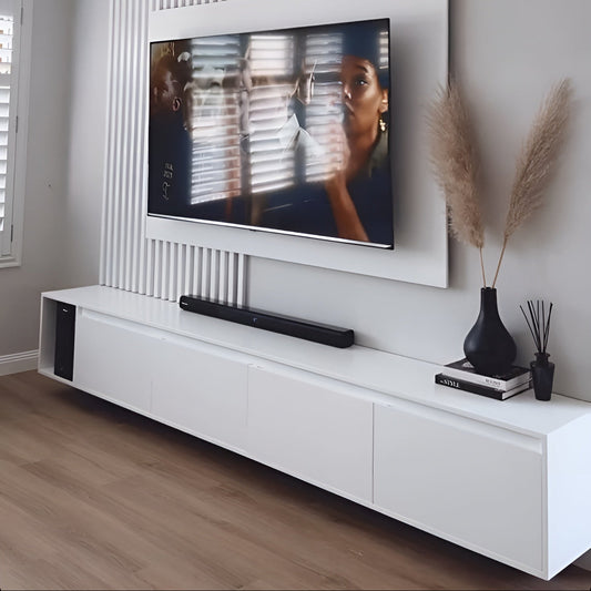 Modern living room with a television mounted on the wall, soundbar below, and decorative items on a white console.