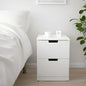 White nightstand with a drawer next to a bed in a bedroom setting.