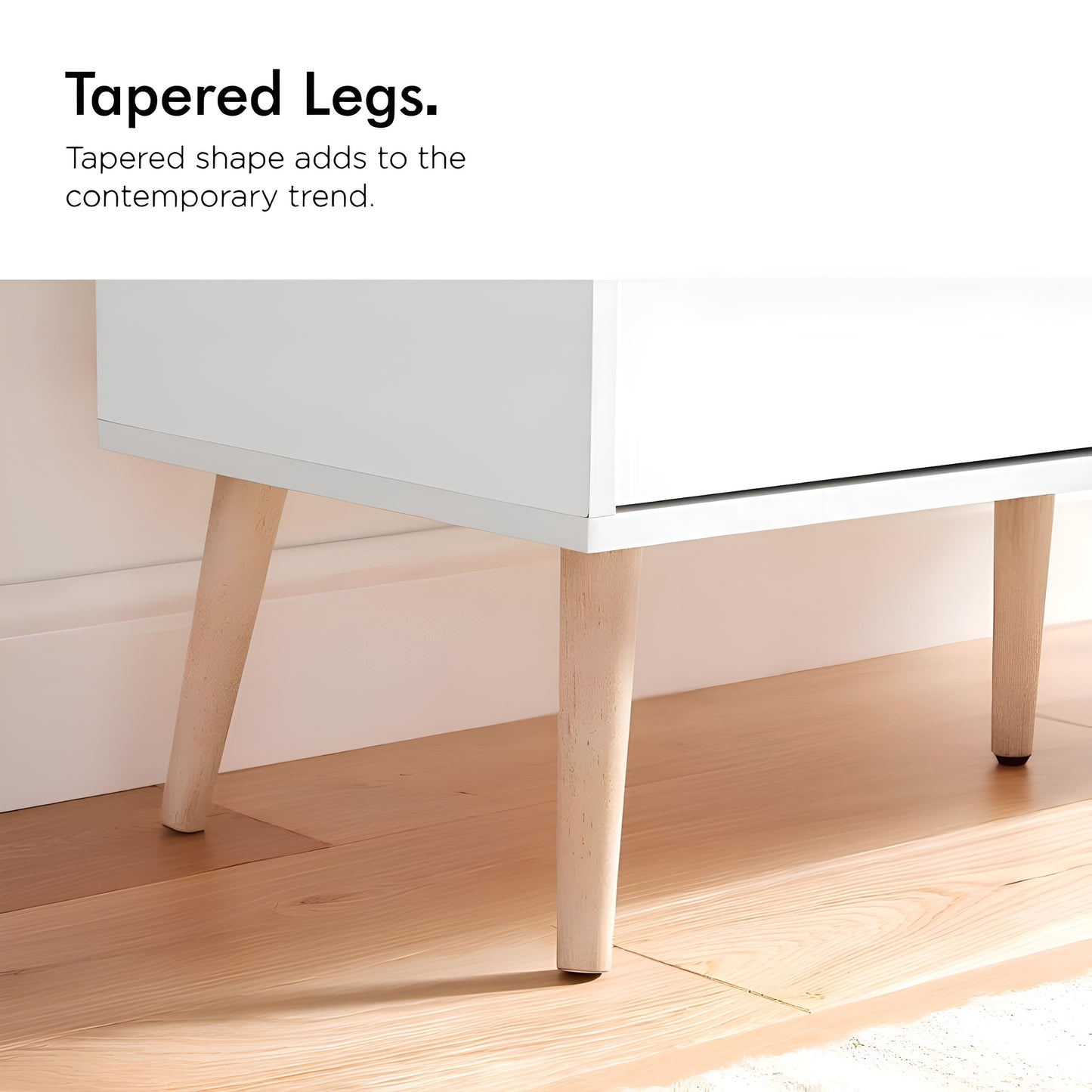 Close-up of a table with tapered legs on a wooden floor.