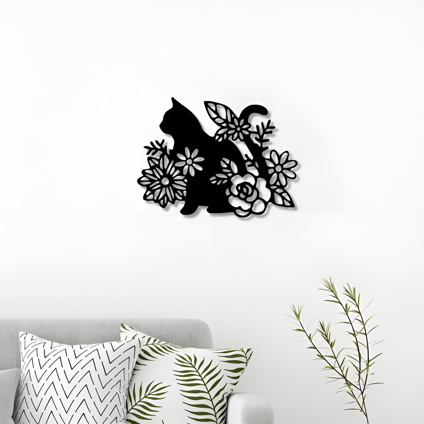 Decorative wall art of a cat among flowers on a white wall above a sofa with patterned cushions.