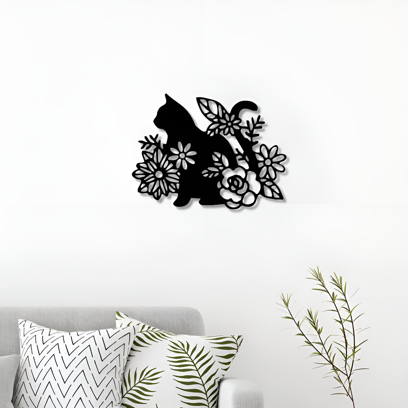 Decorative wall art of a cat among flowers on a white wall above a sofa with patterned cushions.