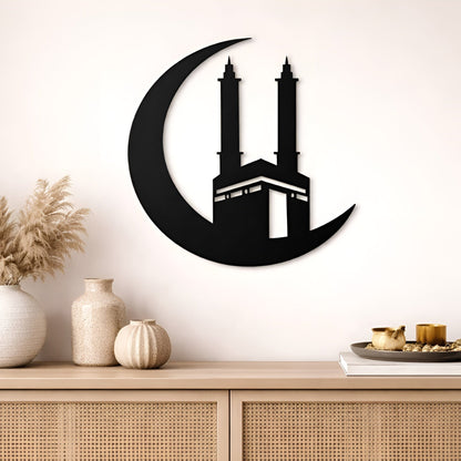 Decorative wall art of a crescent moon with a building silhouette on a beige wall above a wooden cabinet.