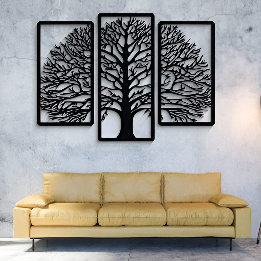 Three black tree-shaped wall art pieces on a gray wall above a yellow sofa.