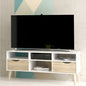 White TV stand with a black TV on top against a geometric wall design.