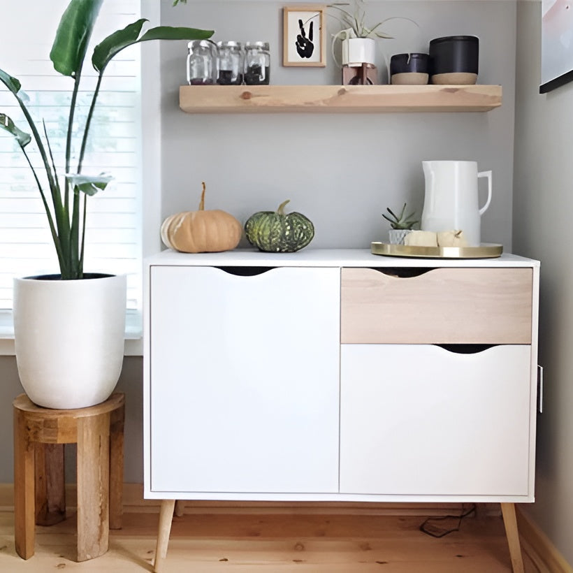 White cabinet with wooden accents in a room with a plant and decorative items.