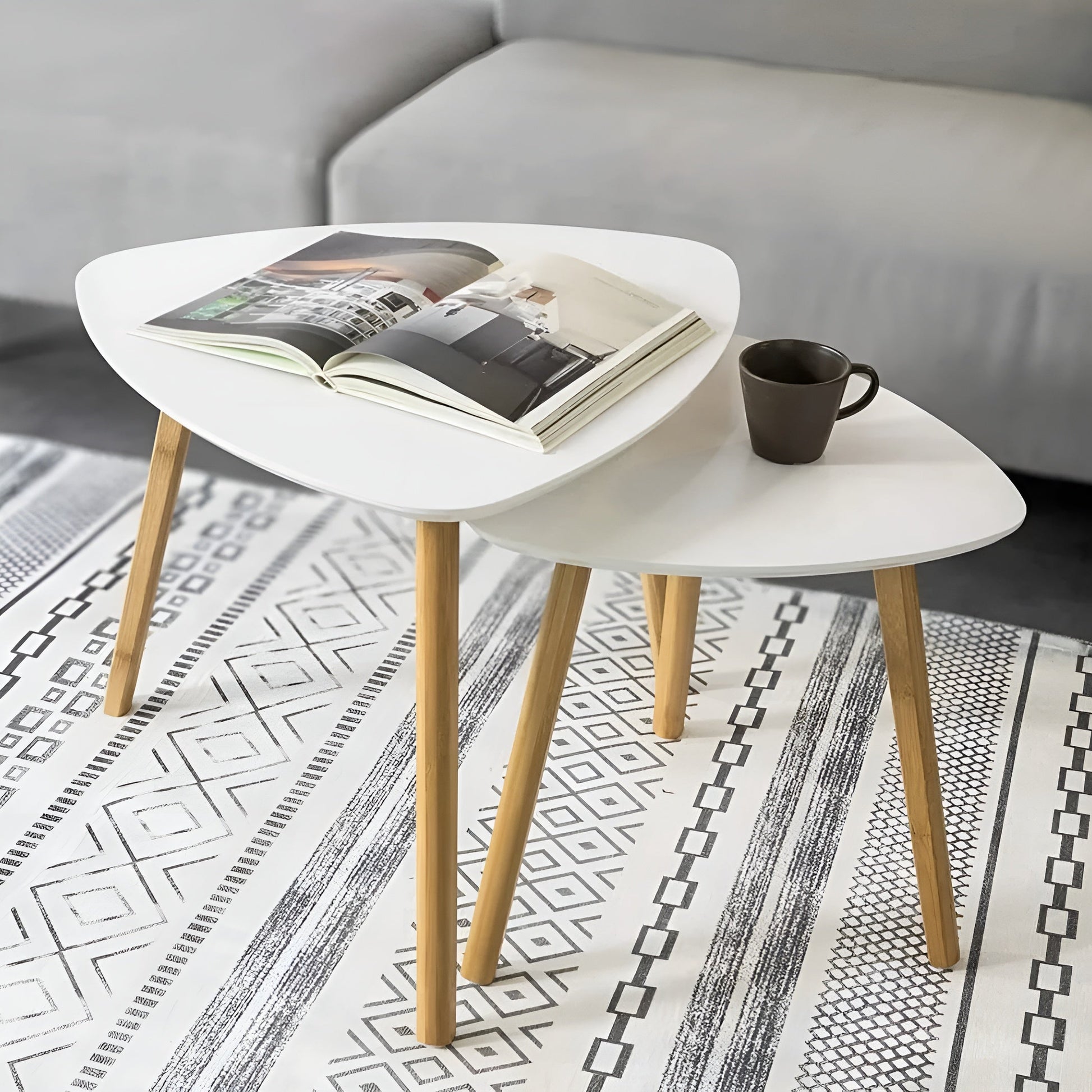 White coffee table with wooden legs holding a magazine and a cup, placed on a patterned rug.