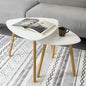 White coffee table with wooden legs holding a magazine and a cup, placed on a patterned rug.
