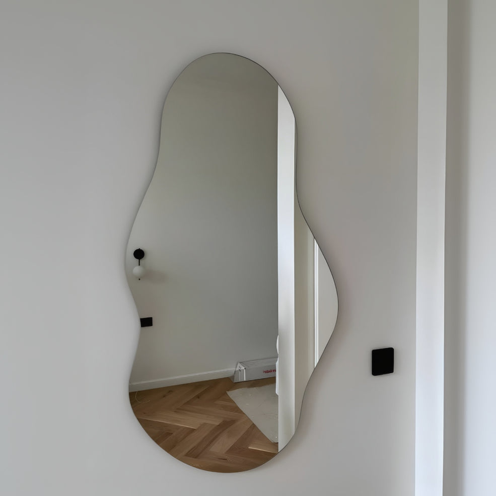 Wavy mirror on a white wall reflecting a room with wooden flooring.