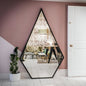 Hexagonal mirror on a pink wall reflecting a room with furniture and decor.
