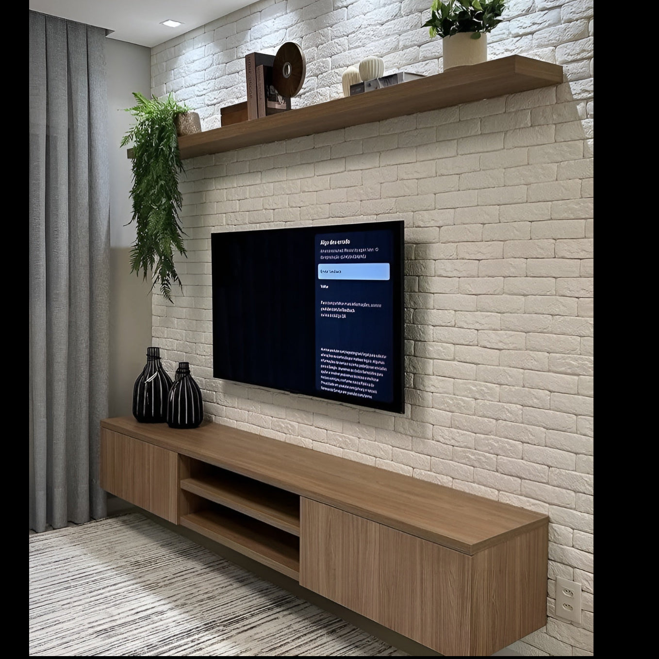 Modern living room with a TV mounted on a white brick wall, wooden shelf, and decorative items.