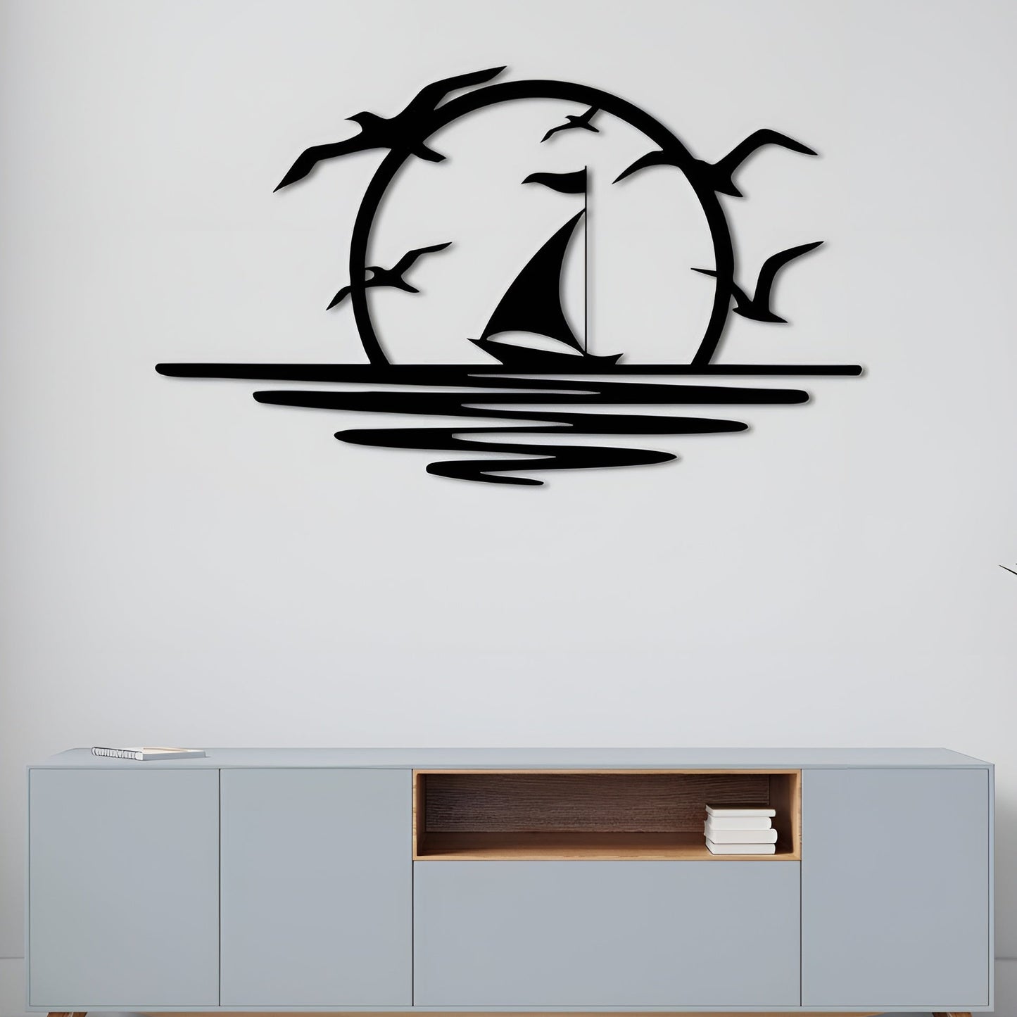 Decorative wall art of a sailboat and birds on a white wall above a light gray cabinet.