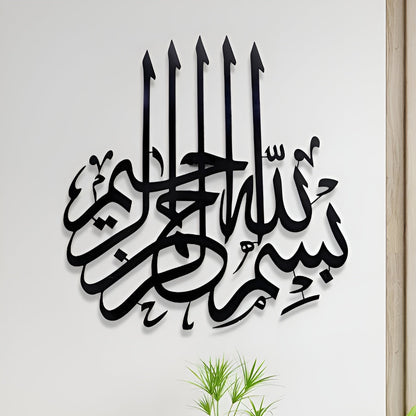 Decorative wall art with Arabic calligraphy on a white wall with plants and a desk.