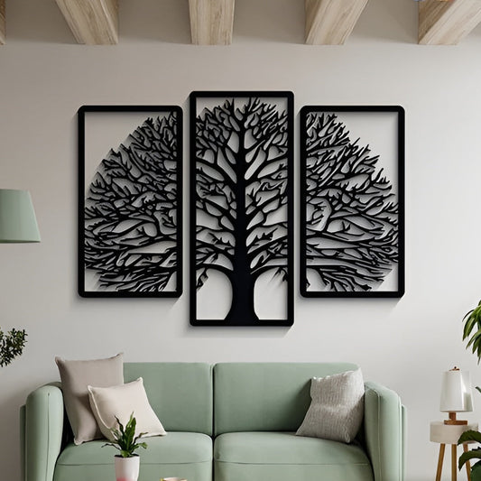 Three black tree-shaped wall art pieces on a white wall above a green sofa.