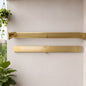 Gold towel racks on a white wall with potted plants below