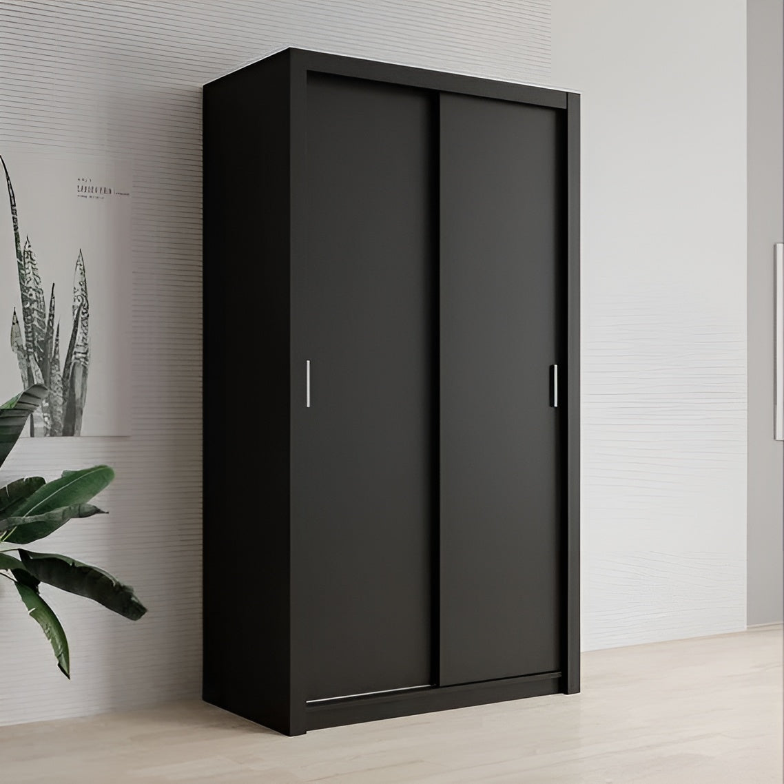 Black wardrobe with sliding doors in a room with a plant and wall art.