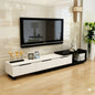 Modern living room with a white TV stand, black-framed TV, and decorative items.