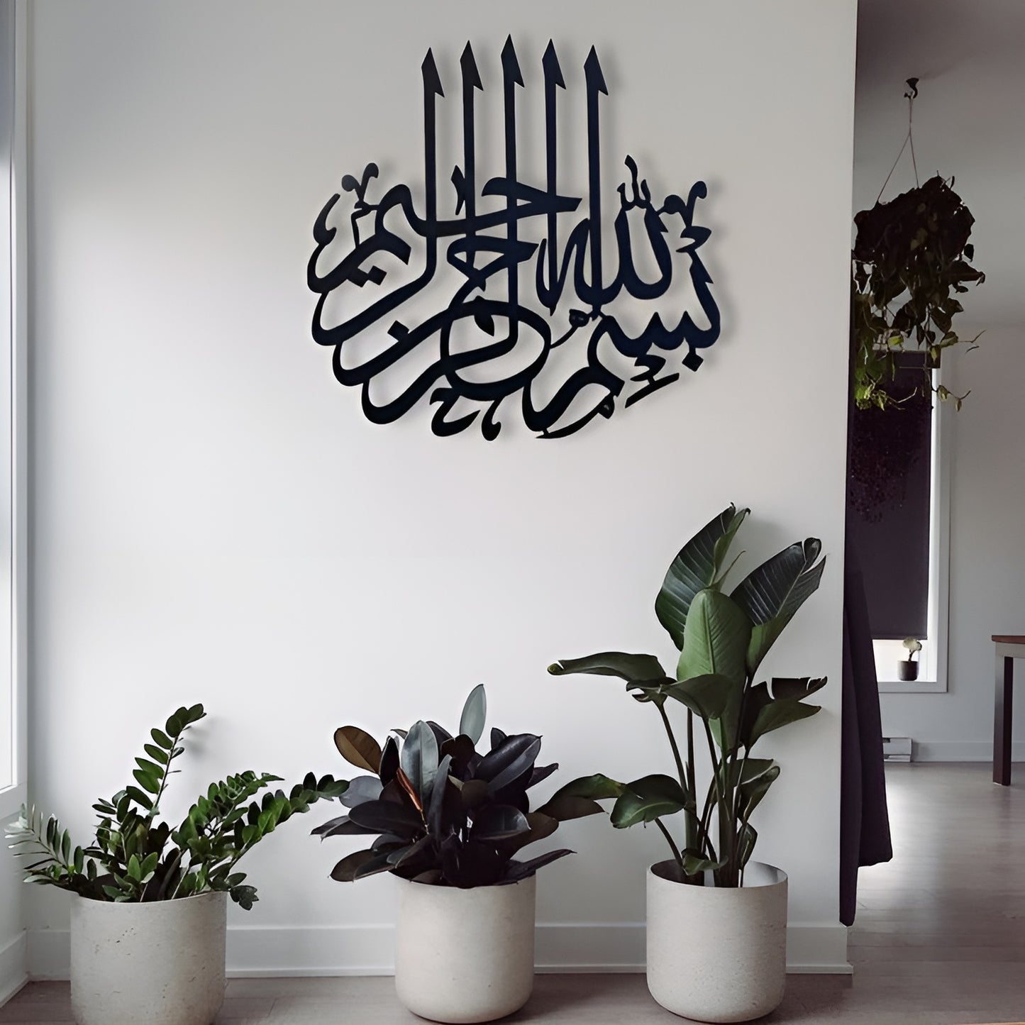 Decorative wall art with Arabic calligraphy in a room with potted plants.