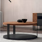 Round wooden coffee table with black metal legs in a modern living room setting.