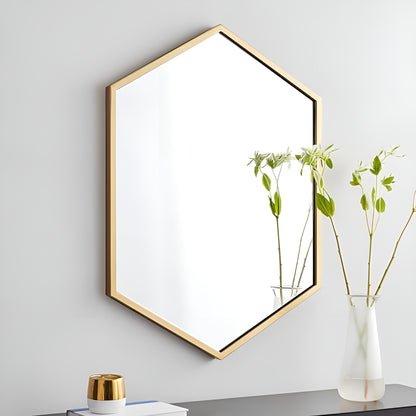 Hexagonal gold-framed wall art on a light gray wall with a vase of plants on a surface.