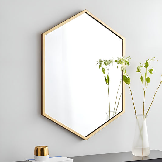 Hexagonal gold-framed wall art on a light gray wall with a vase of plants on a surface.
