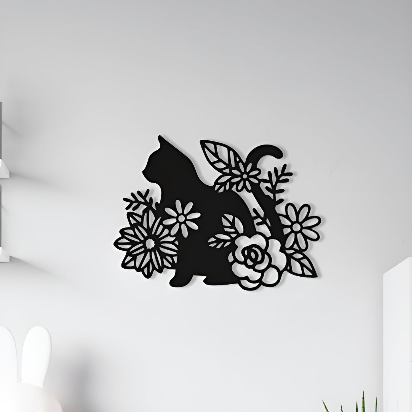 Decorative wall art of a cat silhouette with flowers on a white wall.