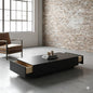 Modern coffee table with storage drawers in a room with a brick wall and large window.