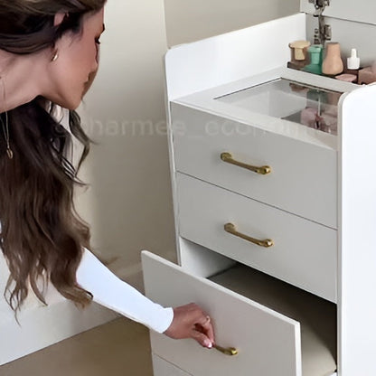 Woman opening a drawer in a white vanity with gold handles.