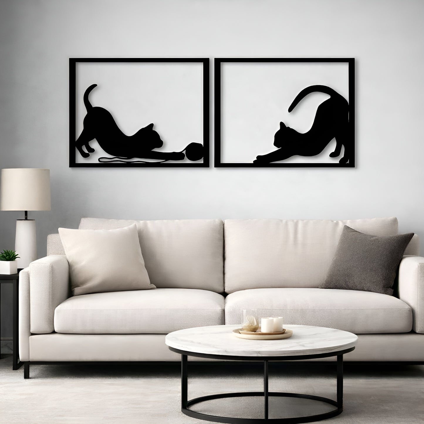 Two black cat silhouettes on a gray wall above a white sofa.