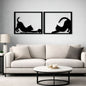Two black cat silhouettes on a gray wall above a white sofa.