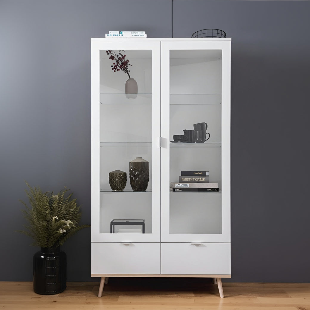 White glass-fronted cabinet with decorative items against a gray wall