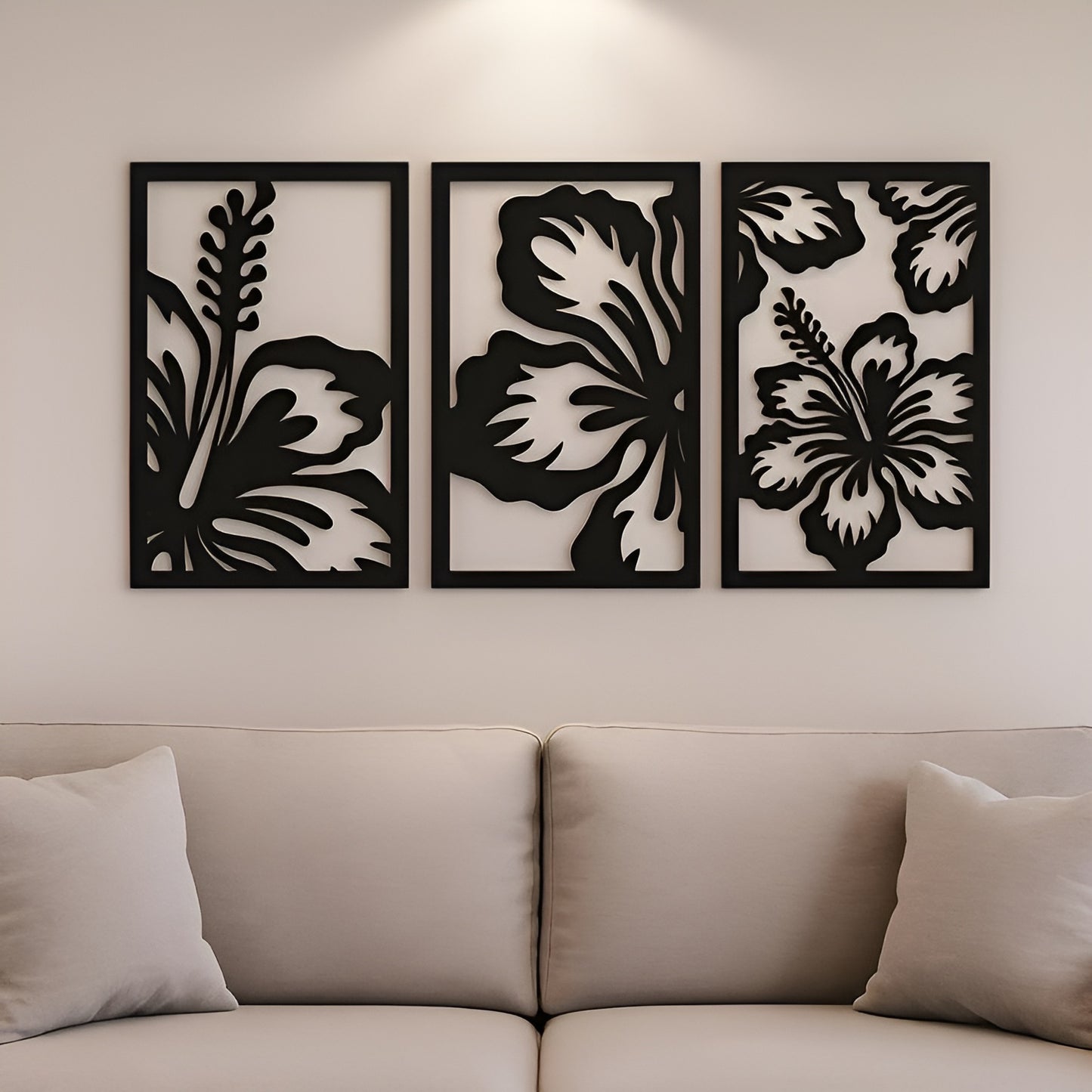 Three black floral wall art panels on a beige wall above a sofa.