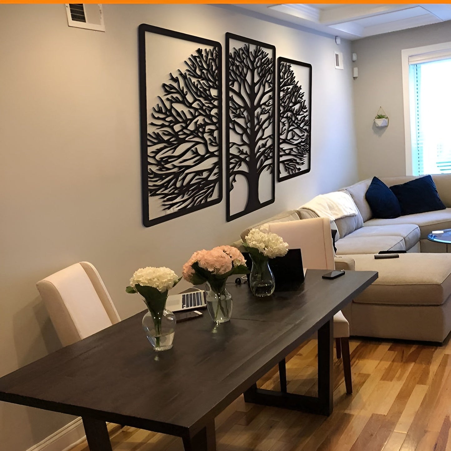 Living room with a dark wooden table, floral arrangements, and wall art.