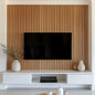 Modern living room with a television mounted on a wooden slat wall, white entertainment console, and decorative vases.