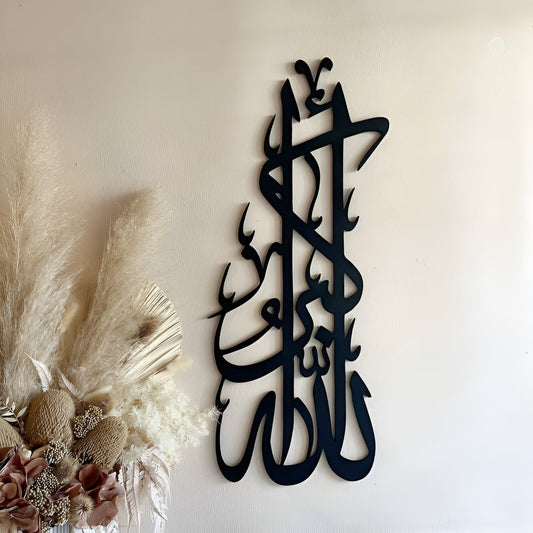Black calligraphy wall art on a white wall with decorative elements.