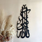 Black calligraphy wall art on a white wall with decorative elements.