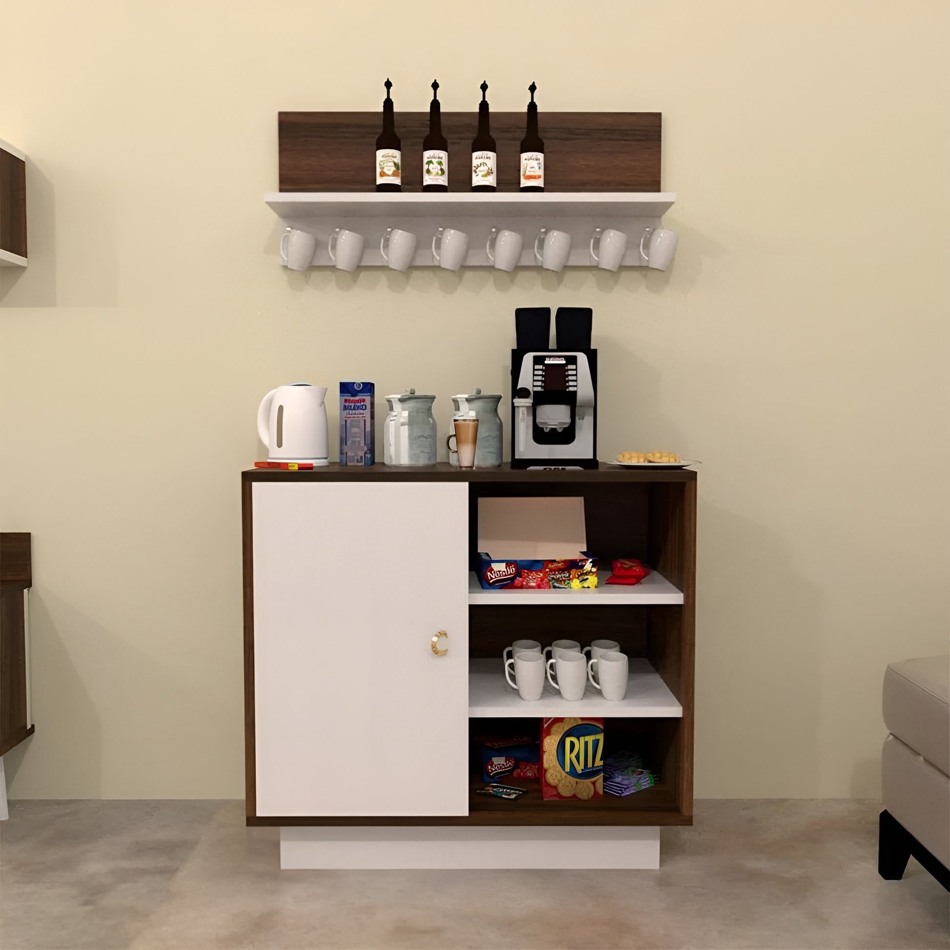 Small kitchenette with coffee maker, cups, and snacks on a beige wall.