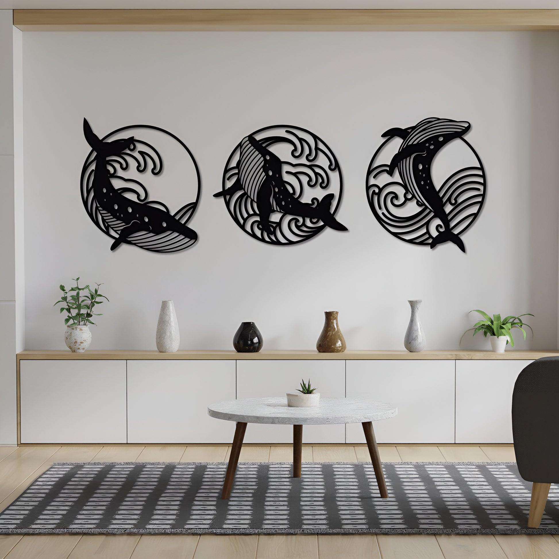 Three black dolphin wall decorations on a white wall above a wooden console table with decorative items.