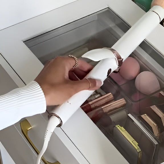 Person using a hair straightener in front of an open drawer with makeup items.