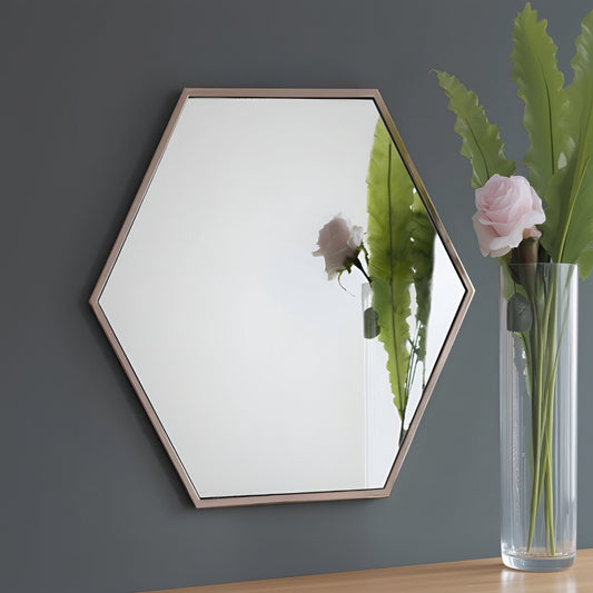 Hexagonal mirror on a gray wall with a side table and flowers in the foreground