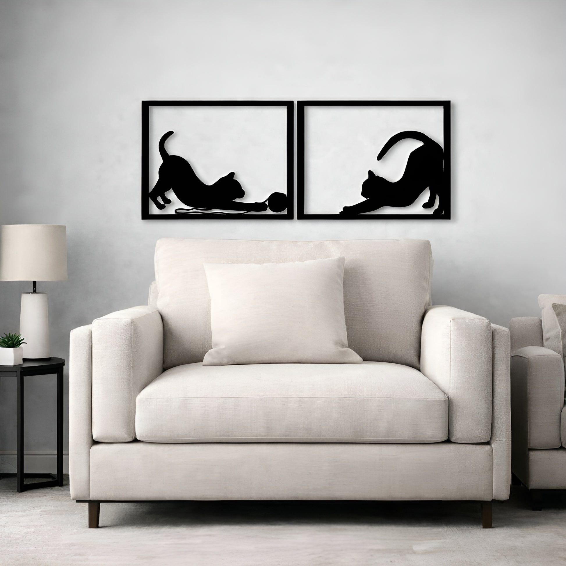 Two black framed wall art pieces of cats on a gray wall above a beige sofa.