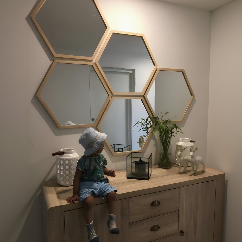 Child sitting on a dresser with hexagonal mirrors above