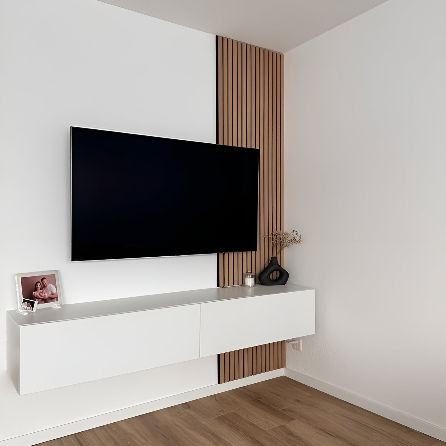 Modern living room with a flat-screen TV mounted on a white wall, below a wooden panel.