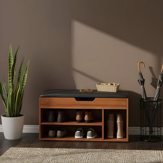 Wooden shoe bench with storage compartments against a brown wall, next to a potted plant and umbrella stand.