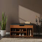 Wooden shoe bench with storage compartments against a brown wall, next to a potted plant and umbrella stand.