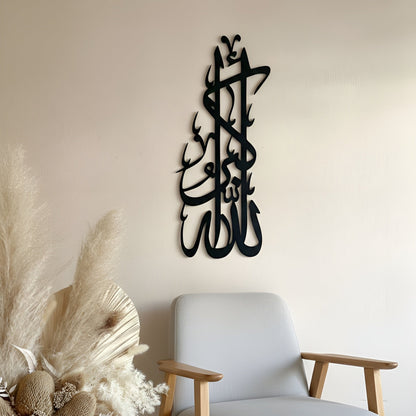 Decorative wall art with Arabic calligraphy above a modern chair and decorative plants.